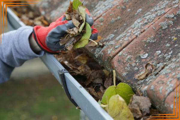 a person with gloves and gloves cleaning leaves off of a gutter gutter